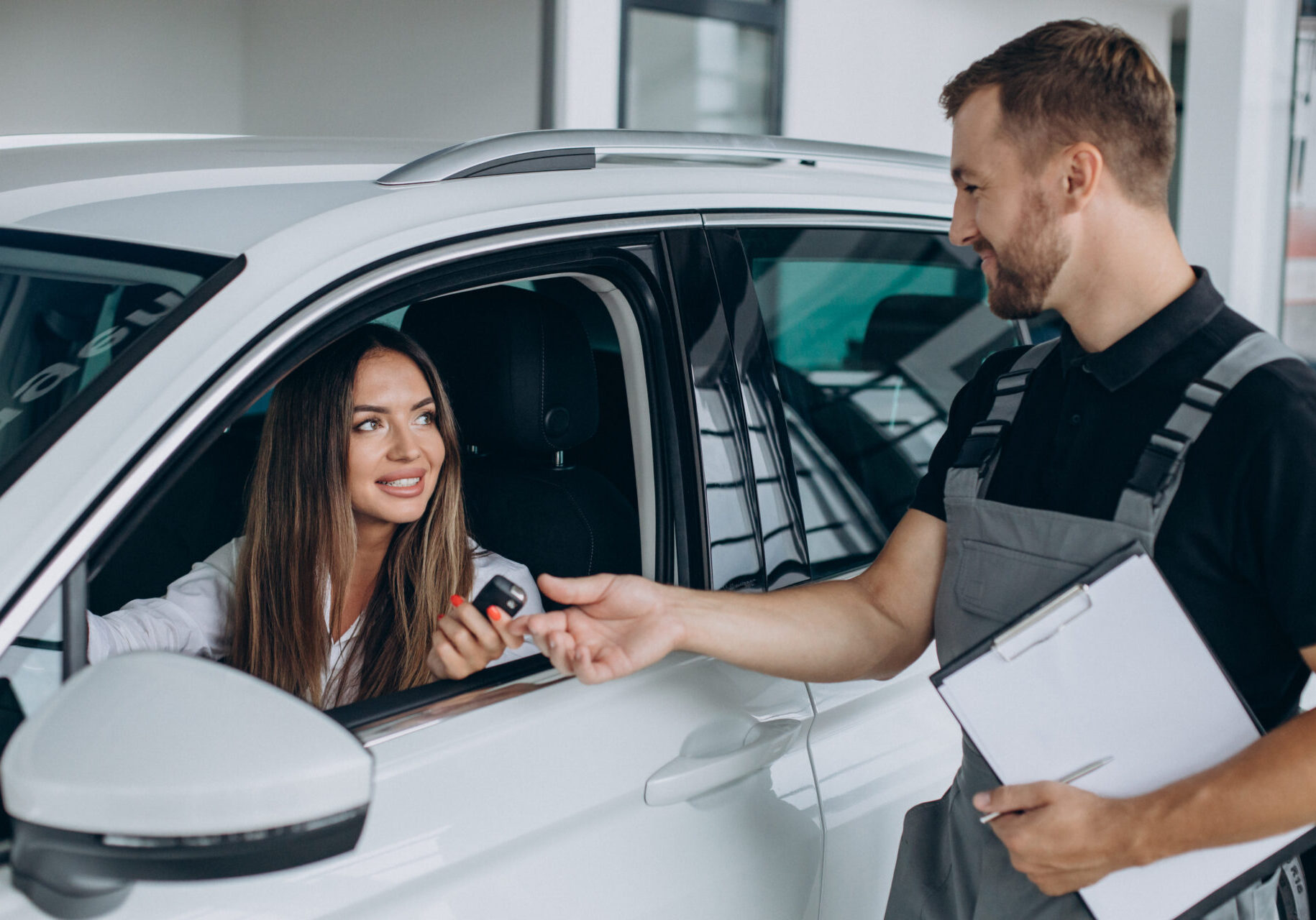 Woman at acr service station checking her car with mechanic